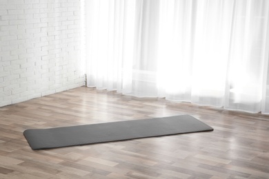 Photo of Grey yoga mat on floor indoors. Space for text