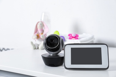 Baby monitor with camera and accessories on table against white background. Video nanny