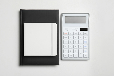 Photo of Calculator and notebooks on white background, flat lay. Tax accounting