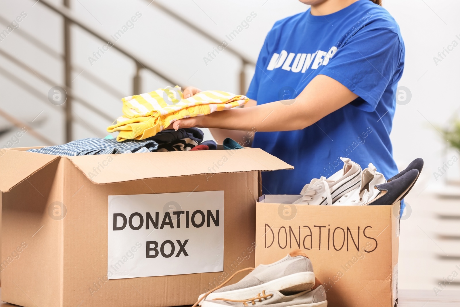 Photo of Female volunteer putting clothes in donation box indoors