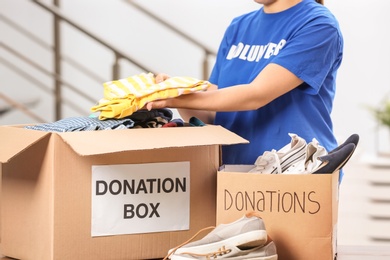 Female volunteer putting clothes in donation box indoors