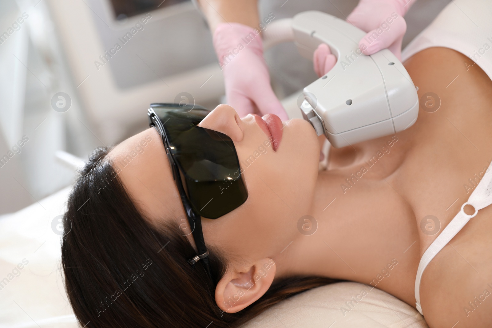 Photo of Young woman undergoing laser epilation procedure in beauty salon