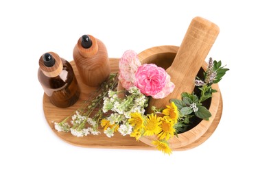 Photo of Bottles of essential oil and wooden mortar with different flowers on white background, top view