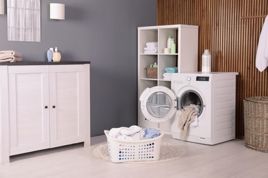 Photo of Washing machine with towels in laundry room interior