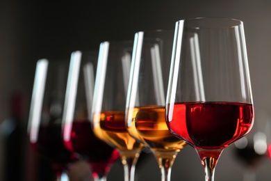 Row of glasses with different wines against blurred background, closeup