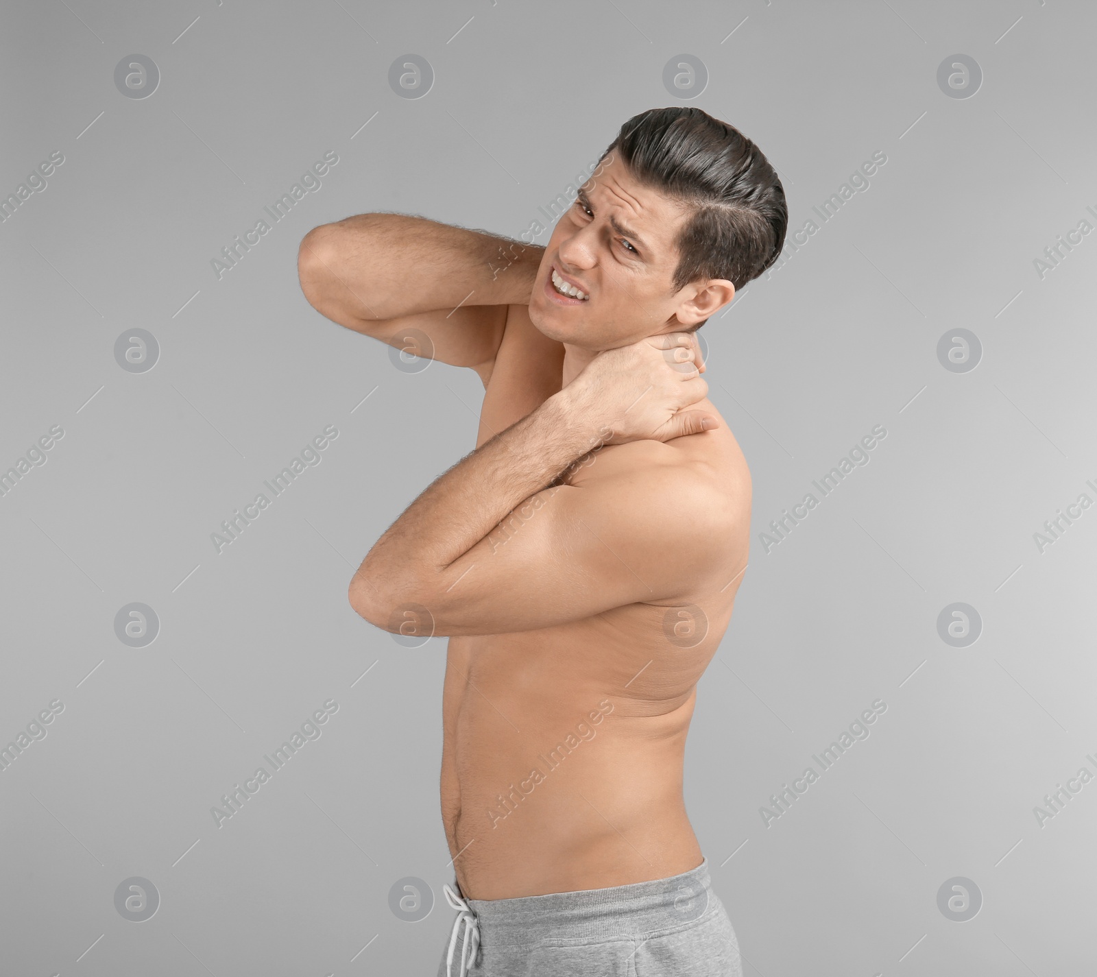 Photo of Young man suffering from neck pain on grey background