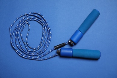 Photo of Skipping rope on blue background, top view