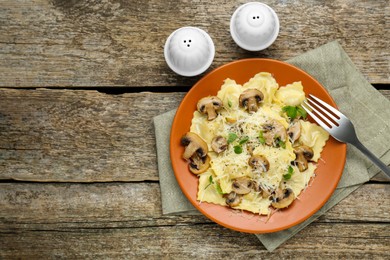 Photo of Delicious ravioli with mushrooms and cheese served on wooden table, flat lay. Space for text