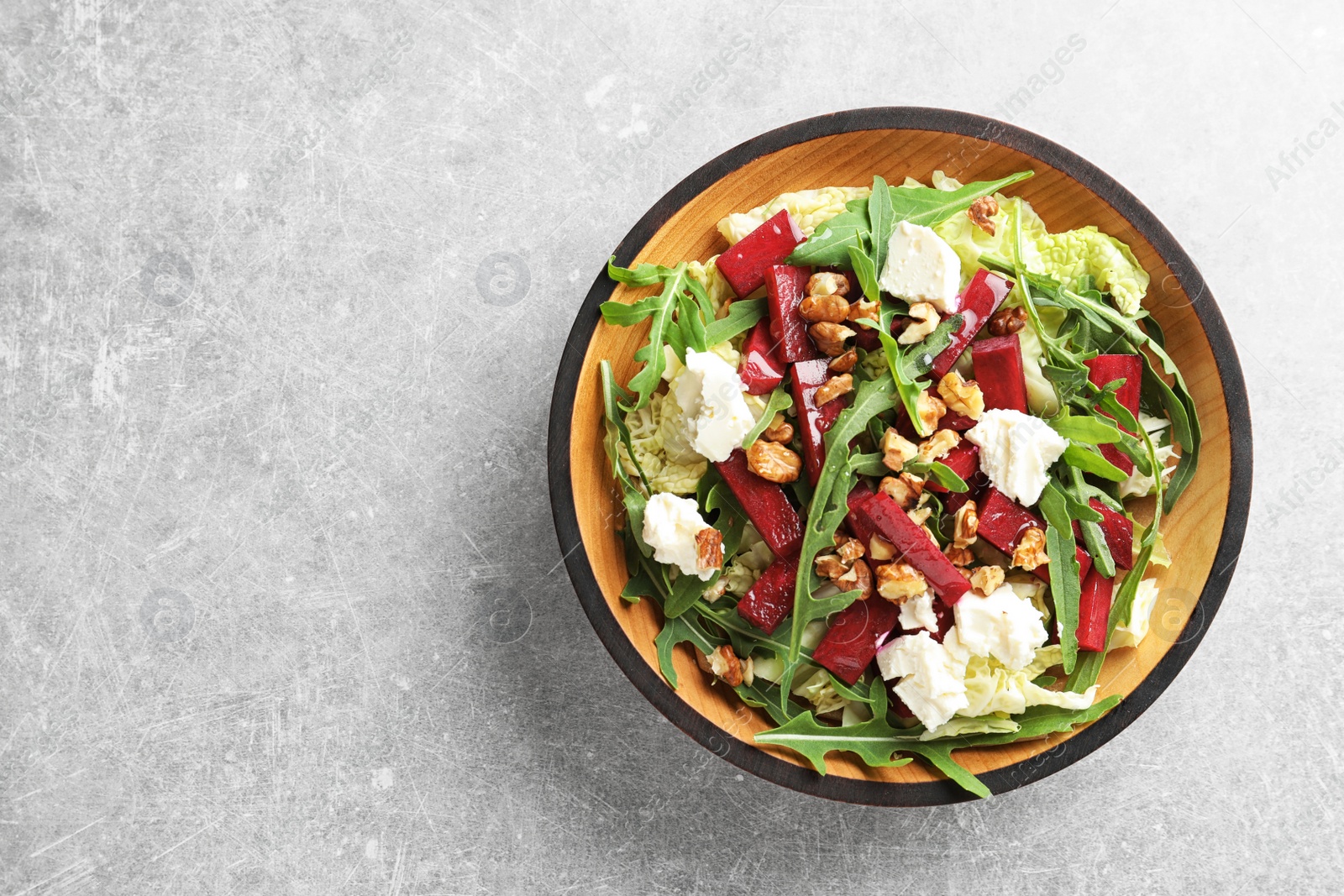 Photo of Bowl of tasty beets salad on gray table, top view with space for text