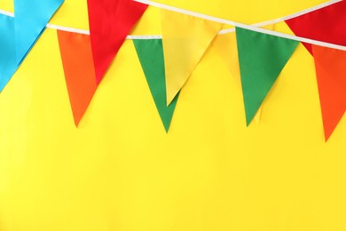 Photo of Buntings with colorful triangular flags on yellow background, space for text