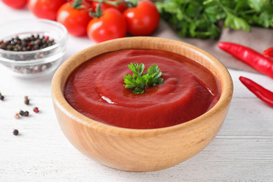 Photo of Delicious tomato sauce on white wooden table, closeup