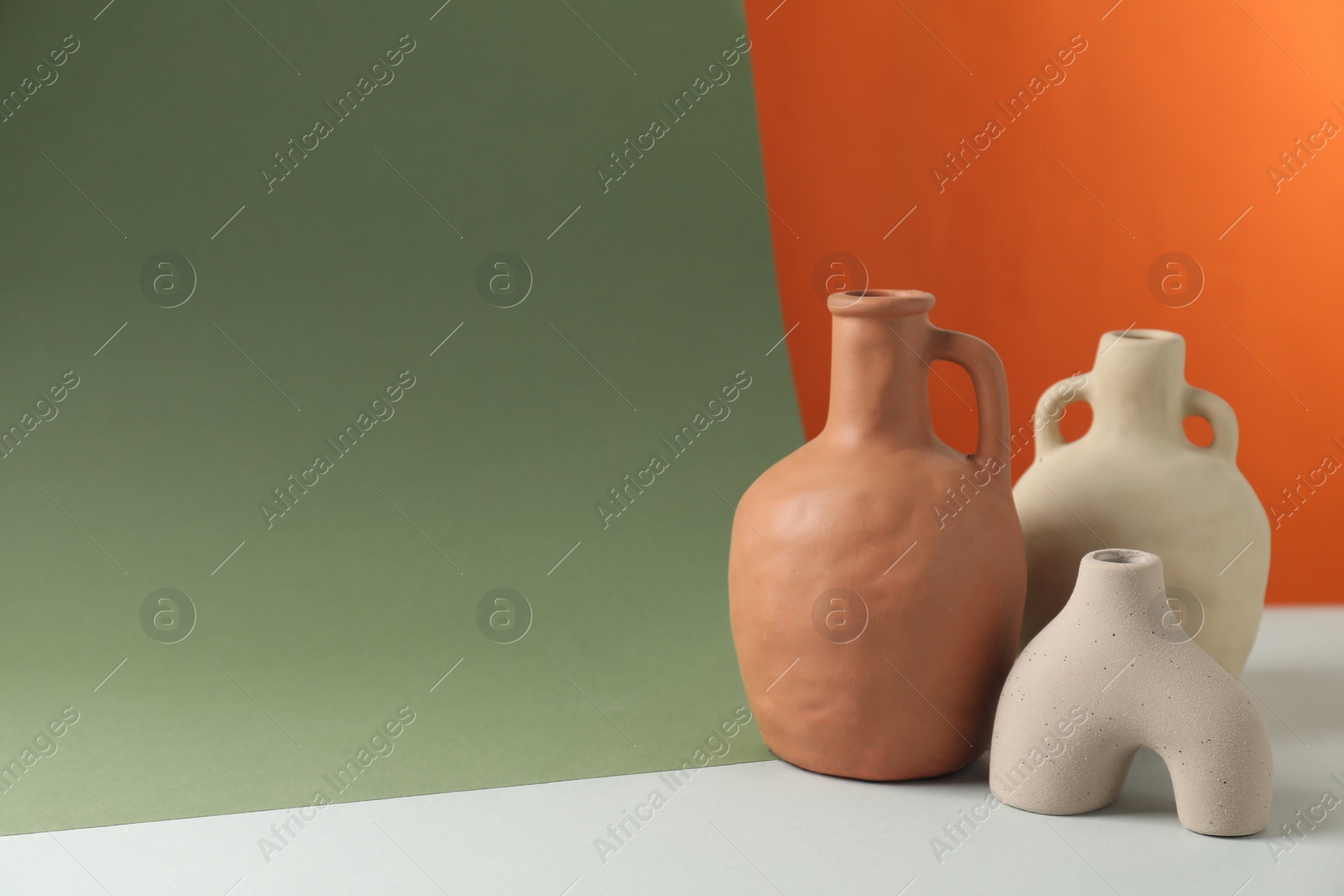 Photo of Clay flagons and vase on color background, space for text