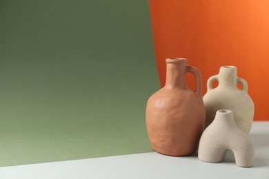 Clay flagons and vase on color background, space for text