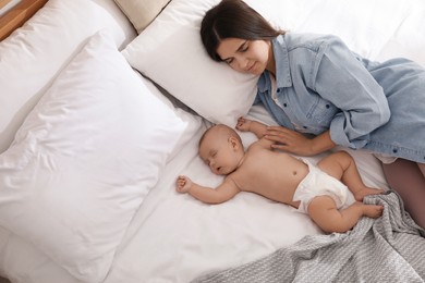 Photo of Mother with her cute baby sleeping on bed, above view