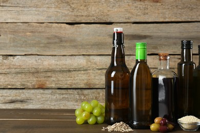 Photo of Vegetable fats. Different cooking oils in glass bottles and ingredients on wooden table, space for text