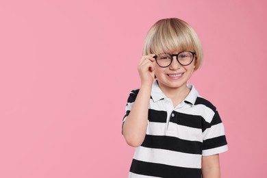 Photo of Cute little boy wearing glasses on pink background, space for text