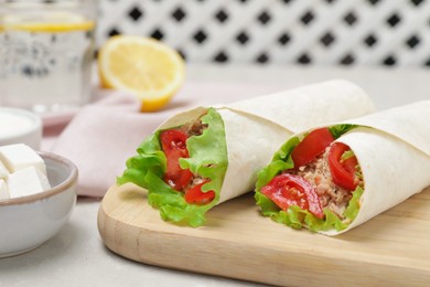 Photo of Delicious tortilla wraps with tuna on light grey table, closeup