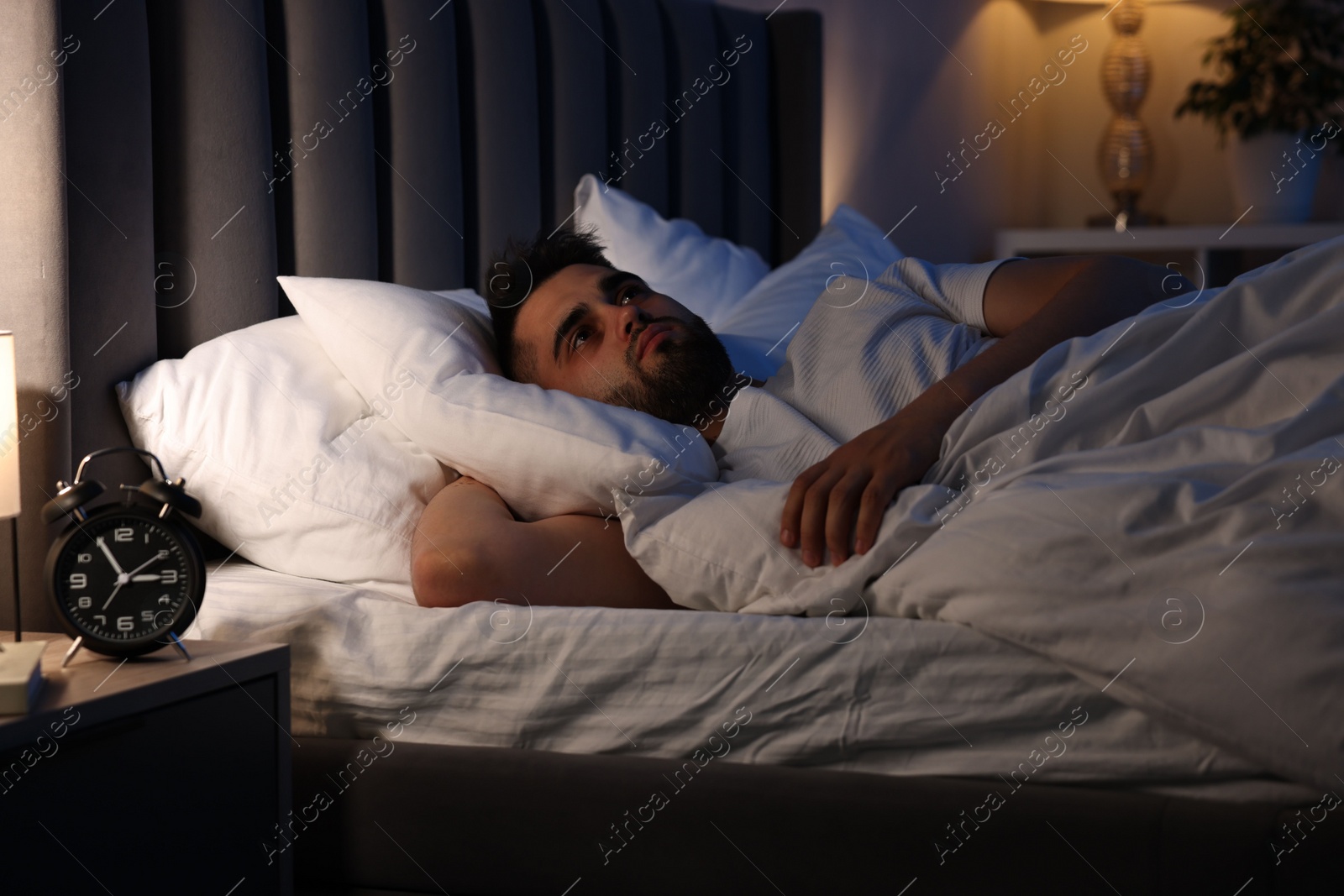 Photo of Frustrated man suffering from insomnia in bed