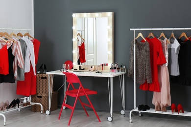 Photo of Stylish room with dressing table, mirror and wardrobe racks