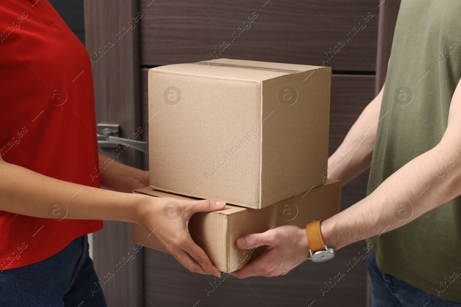 Photo of Courier giving parcel to customer at house entrance, closeup