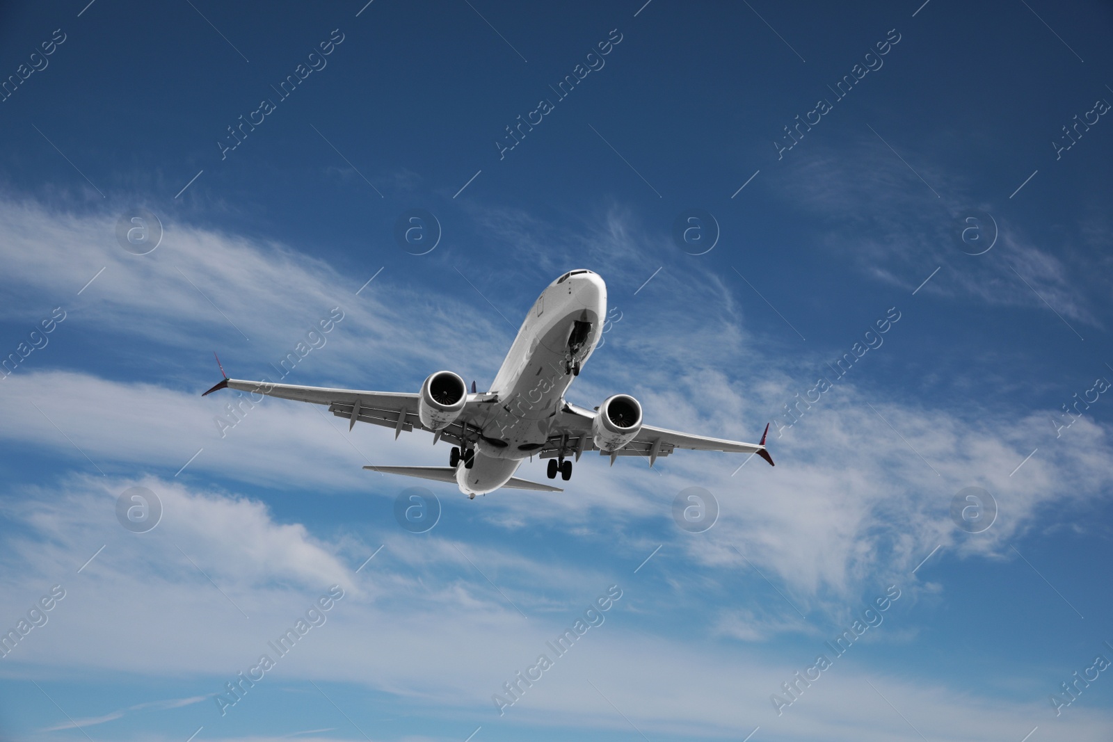 Photo of Modern white airplane flying in cloudy sky, low angle view
