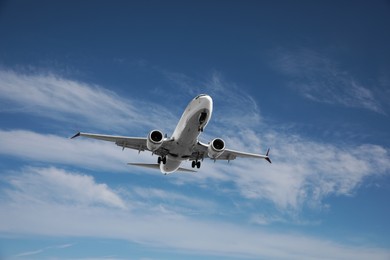 Photo of Modern white airplane flying in cloudy sky, low angle view