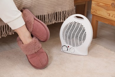 Woman near modern electric fan heater indoors, closeup