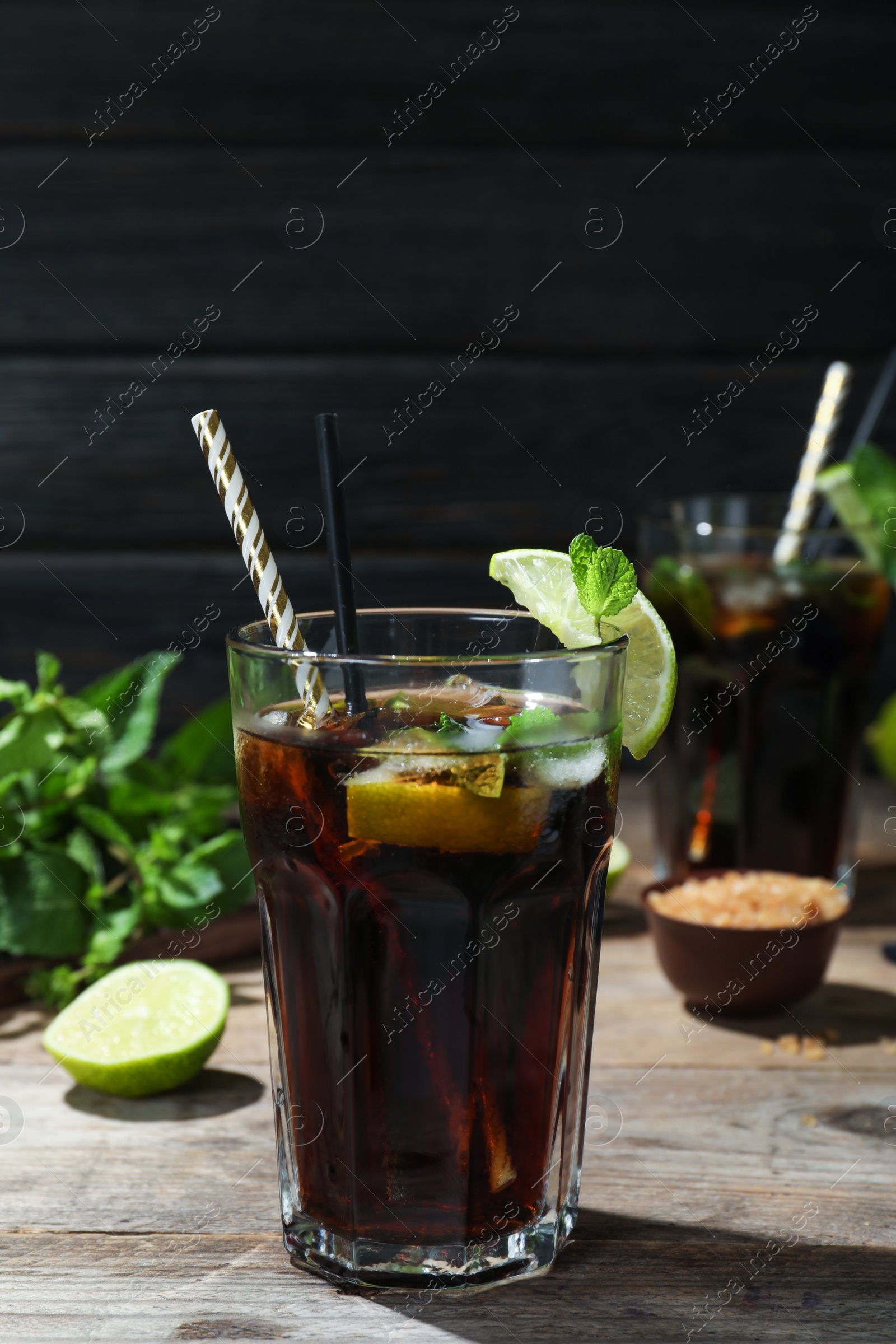 Photo of Glass of delicious cocktail with ice on table against dark wooden background