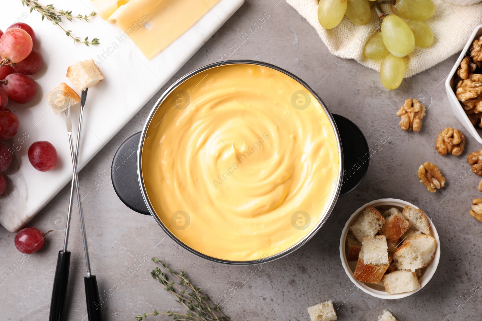 Photo of Flat lay composition with pot of delicious cheese fondue on gray table