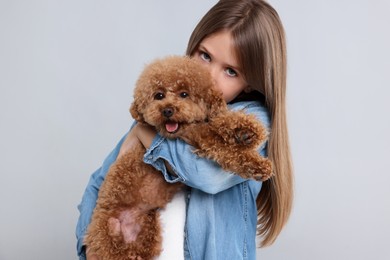 Little child with cute puppy on light grey background. Lovely pet