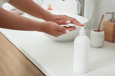 Beautiful young woman using washing gel in bathroom, closeup. Skin care cosmetic