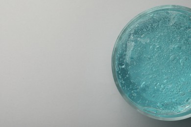 Jar of blue cosmetic gel on light background, top view. Space for text