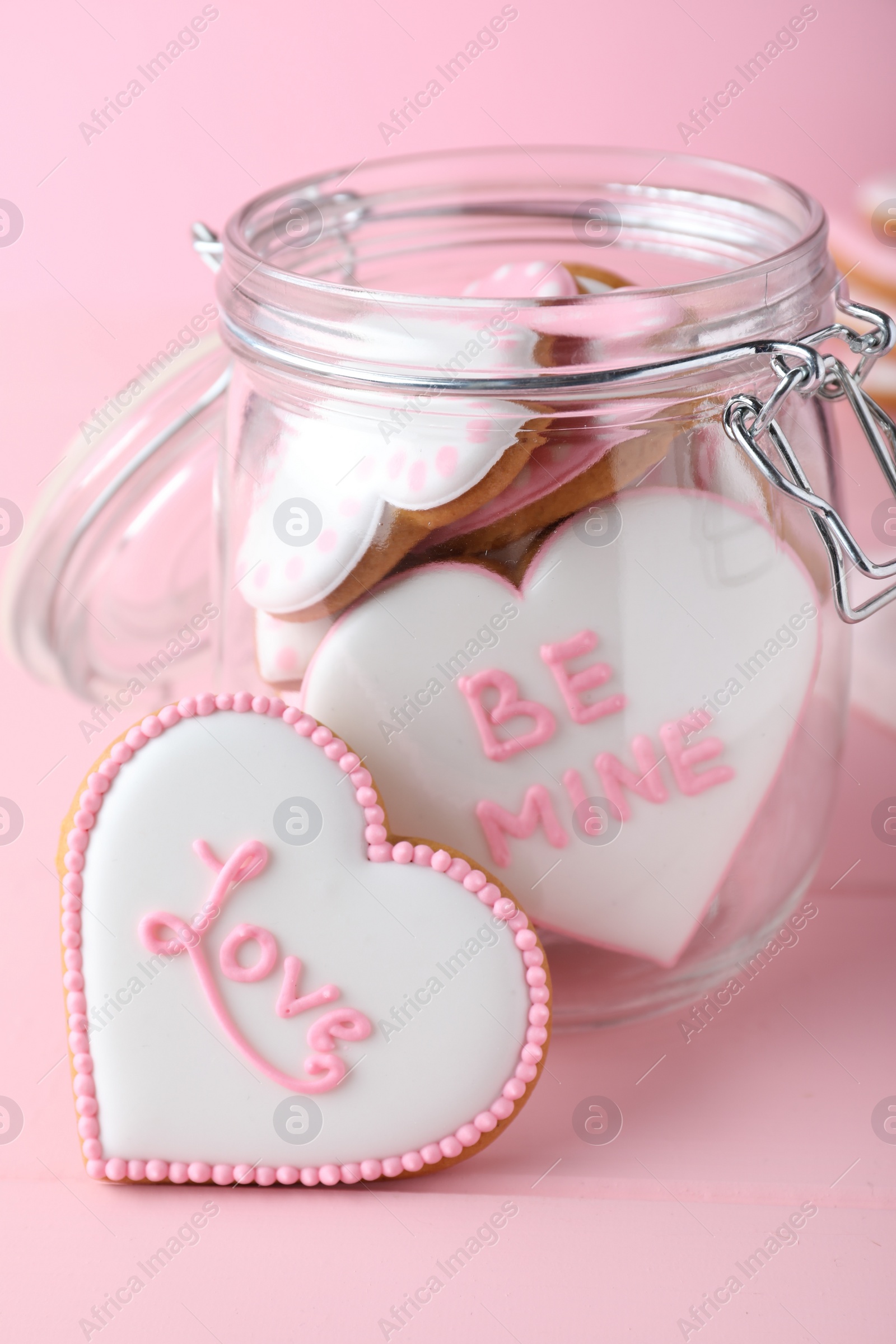 Photo of Glass jar and decorated heart shaped cookies on pink background. Valentine's day treat