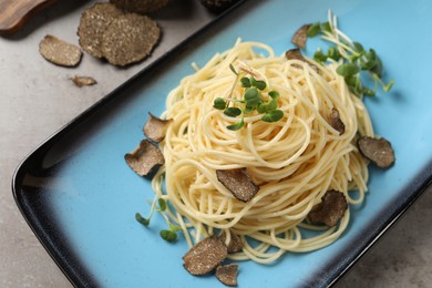 Delicious pasta with truffle slices and microgreens served on light grey table, above view