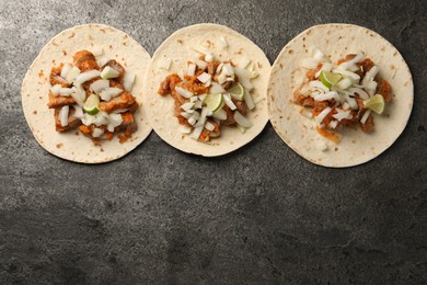 Delicious tacos with vegetables, meat and lime on grey textured table, flat lay. Space for text