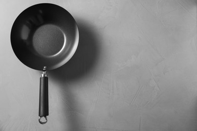 Photo of Empty iron wok on grey textured table, top view with space for text. Chinese cookware