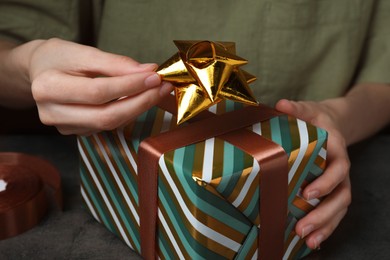 Photo of Woman wrapping gift at grey table, closeup