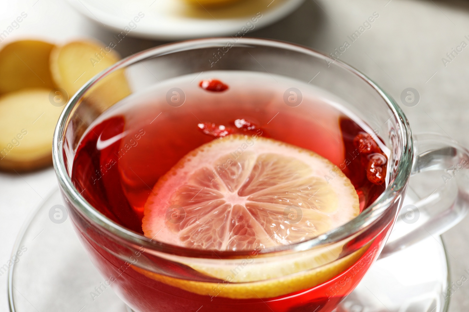 Photo of Glass cup of healthy goji tea with lemon slice on table, closeup