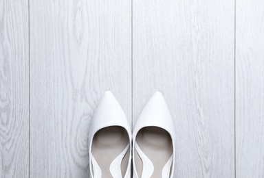 Photo of Pair of wedding high heel shoes on white wooden floor, flat lay. Space for text