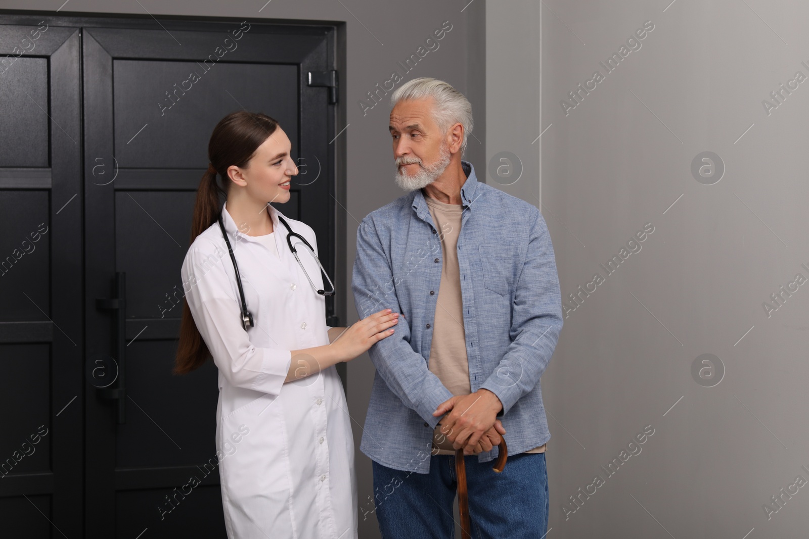 Photo of Young healthcare worker assisting senior man indoors