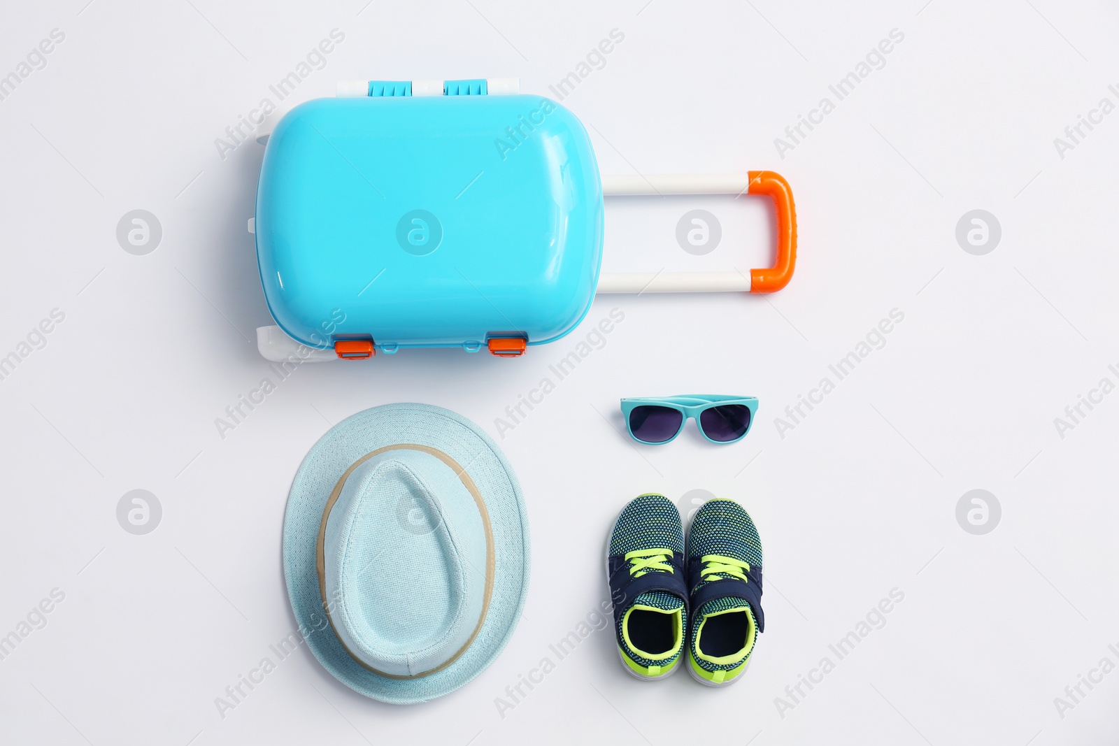 Photo of Composition with blue suitcase and child accessories on white background, top view. Summer vacation