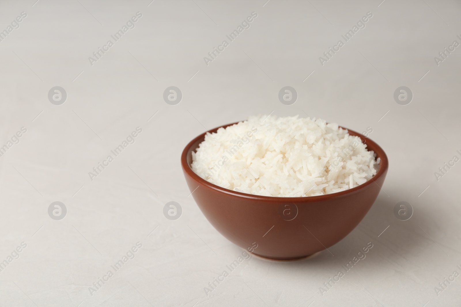 Photo of Bowl of boiled rice on light table. Space for text