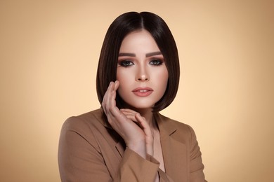 Portrait of stylish young woman with brown hair on beige background