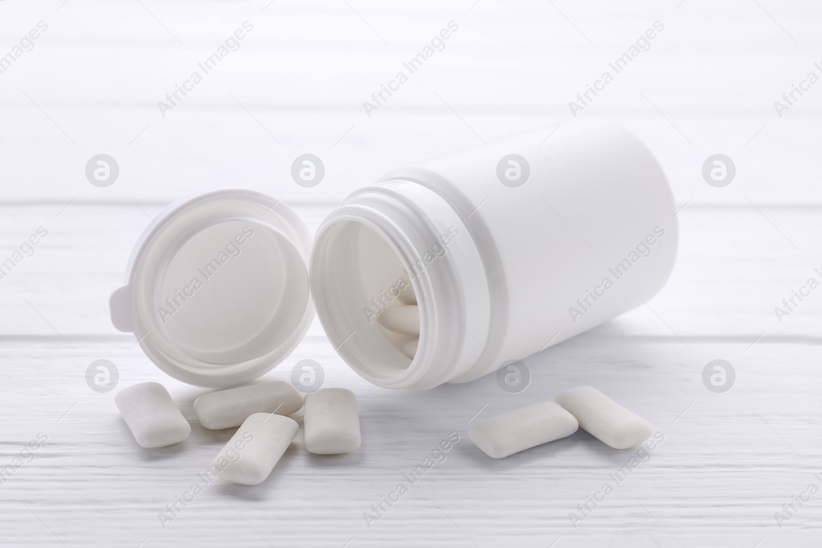 Photo of Jar with chewing gums on white wooden table