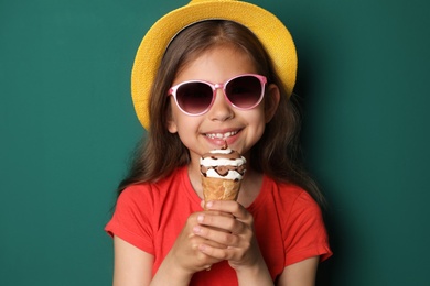 Cute little girl with delicious ice cream against color background