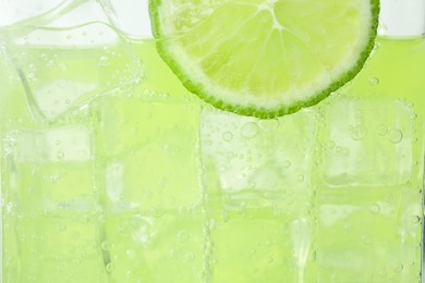 Closeup view of cold refreshing drink with ice and lime slice in glass