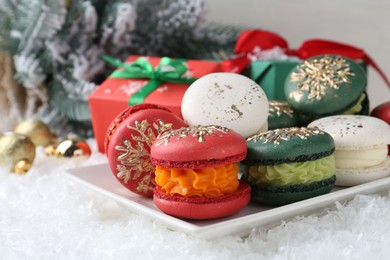 Photo of Beautifully decorated Christmas macarons, gift boxes and festive decor on snow, closeup