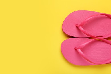 Photo of Stylish pink flip flops on yellow background, top view. Space for text