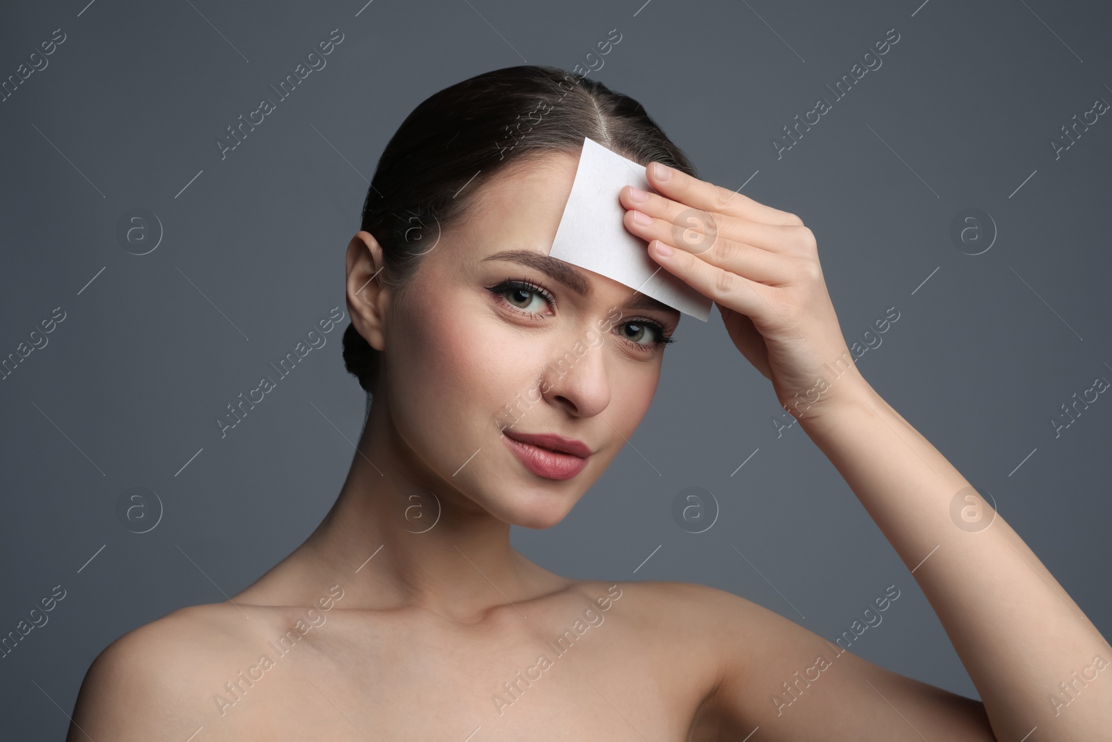 Photo of Beautiful woman using mattifying wipe on grey background