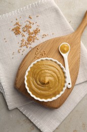 Photo of Tasty mustard sauce and dry seeds on light textured table, flat lay